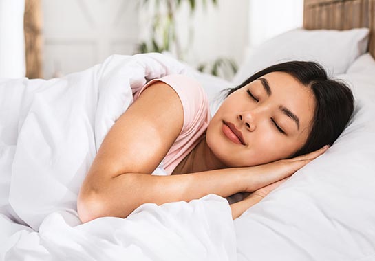Mulher asiática dormindo em lençóis brancos - Clínica do Pulmão